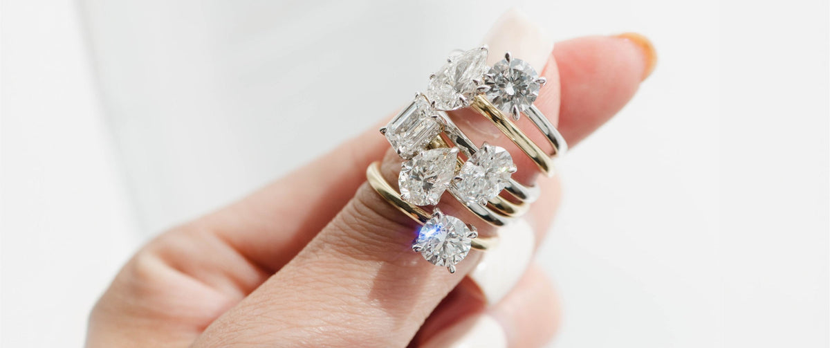Hand holding diamond engagement rings with different cuts