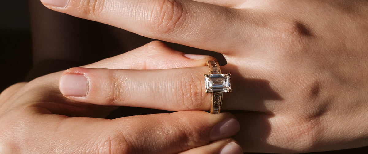 Woman Wearing An Emerald Cut Engagement Ring in Yellow Gold