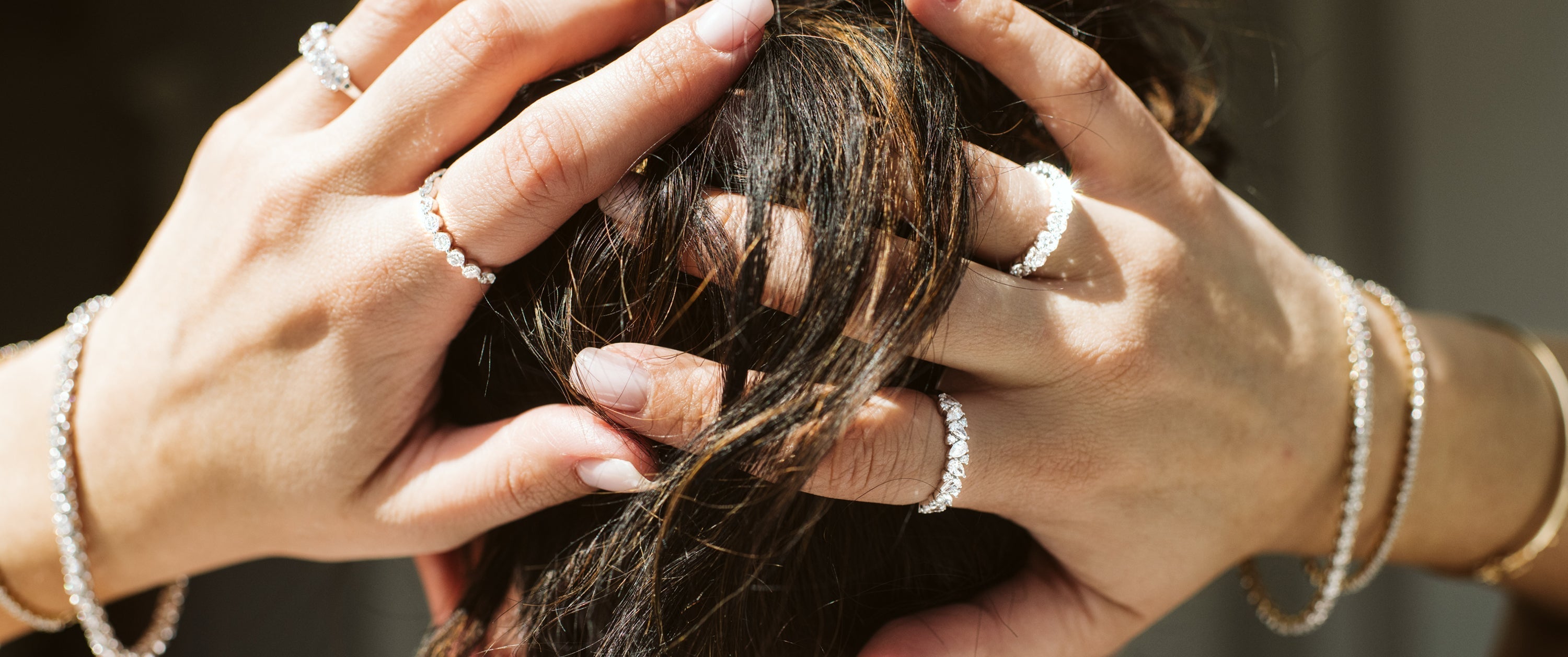 Woman photography fixing her hair with multiple diamond wedding bands and bracelets.