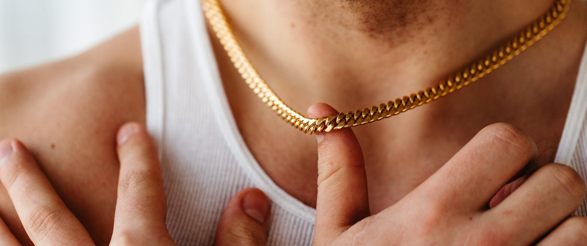 Close up photo of a man wearing a white shirt and gold chain.