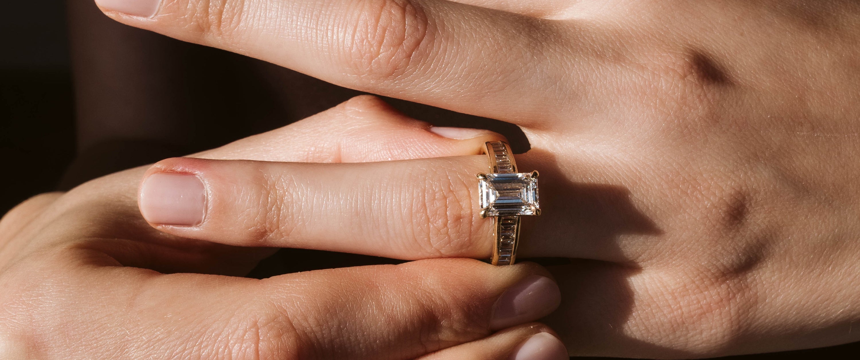 Woman Wearing An Emerald Cut Engagement Ring in Yellow Gold